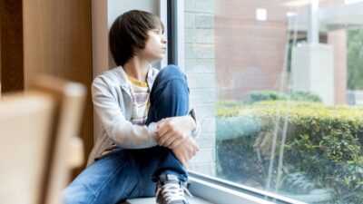 tiener jongen staart uit raam naar buiten